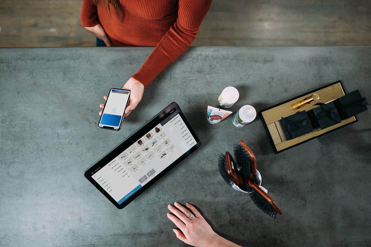 person holding smartphone beside tablet computer